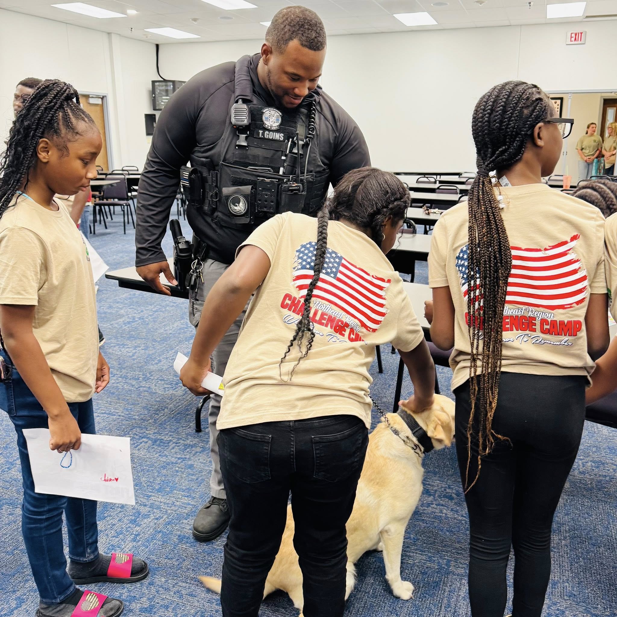 A policeman showing his dog to three girls.